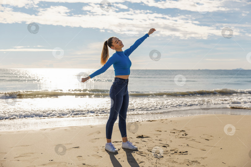 Скачать Молодая девушка-гимнастка занимается фитнесом на пляже фотосток Ozero