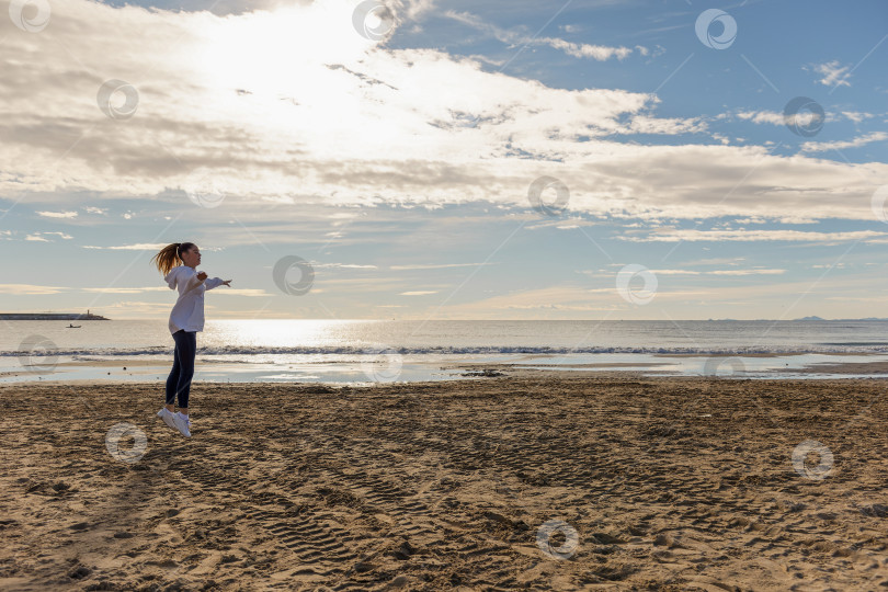 Скачать Красивая энергичная молодая женщина занимается гимнастикой на пляже фотосток Ozero