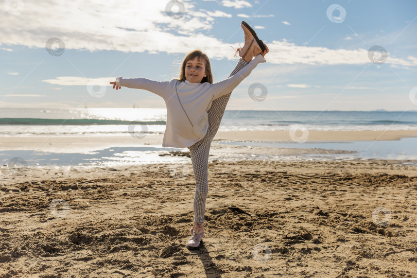 Скачать Молодая девушка-гимнастка занимается фитнесом на пляже фотосток Ozero