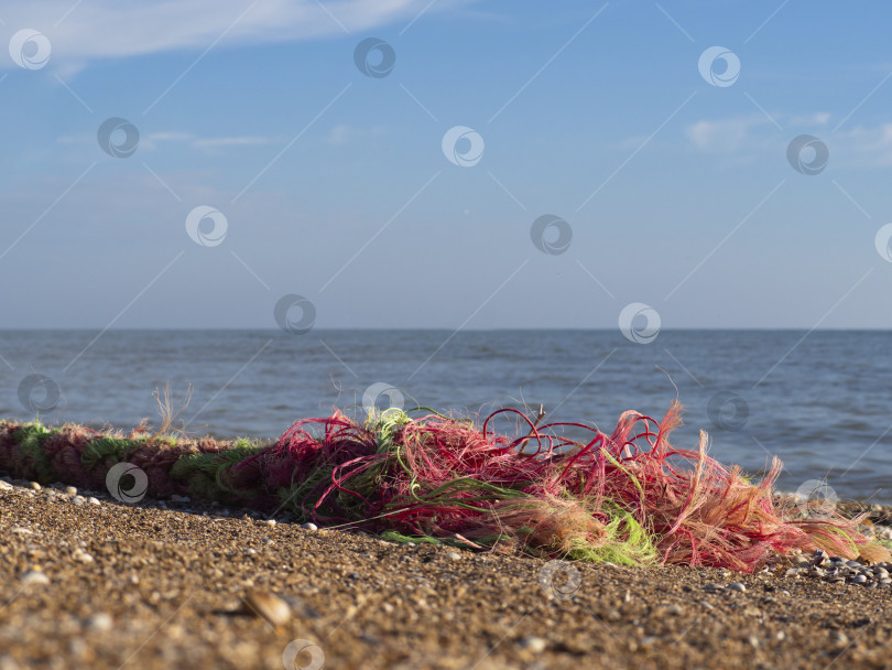 Скачать Растрепанный разноцветный канатный канат на песчаном пляже на фоне моря и неба. фотосток Ozero