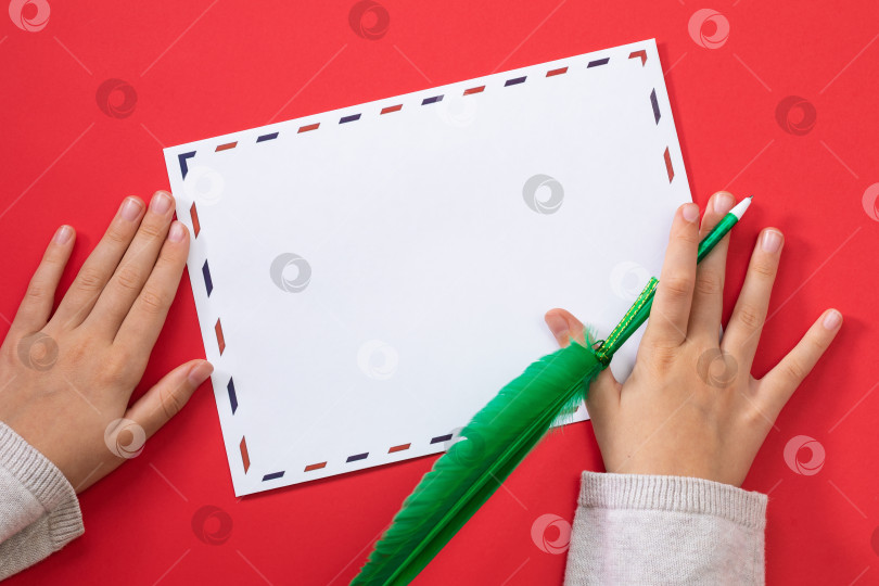 Скачать Детские руки с ручкой в форме пера и пустым почтовым конвертом на цветном фоне, шаблон для дизайнера фотосток Ozero