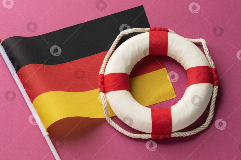 Скачать Копилка, спасательный круг и флаг Германии на цветном фоне, концепт на тему помощи из Германии фотосток Ozero