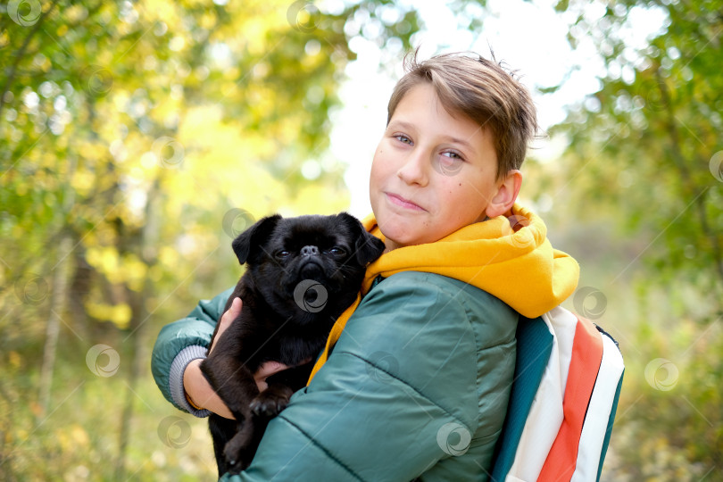 Скачать Мальчик-подросток с собакой гуляют в парке солнечной желтой осенью. Дружба мальчика и животного, владельца животного. Портрет мальчика с домашним животным. фотосток Ozero