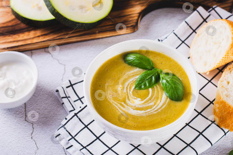 Скачать Вкусный суп-пюре из кабачков в миске и кусочки хлеба на столе фотосток Ozero