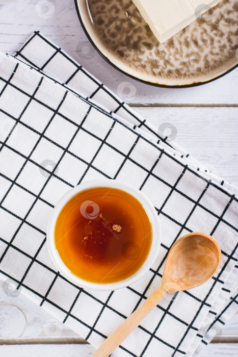 Скачать Вкусный соус из растопленного коричневого сливочного масла в миске на столешнице в вертикальном положении фотосток Ozero