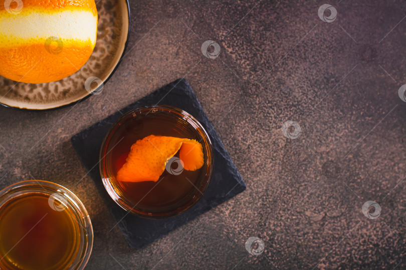 Скачать Крепкий алкогольный коктейль с коричневым маслом и апельсиновой цедрой в бокале вид сверху фотосток Ozero