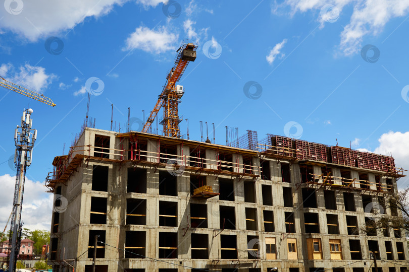 Скачать Строительство жилого дома. Кран на строительной площадке на фоне голубого неба. фотосток Ozero