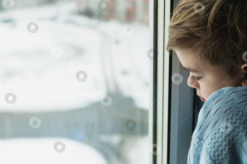Скачать Маленький мальчик смотрит в окно на улицу фотосток Ozero