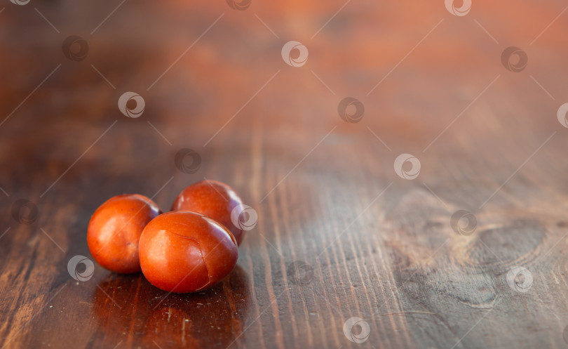 Скачать Крупный план спелых вкусных ягод зизифуса (impossible, китайская финиковая ягода) на деревянном столе, выборочный фокус, малая глубина резкости, свободное место для текста и оформления. Коричневые плоды трескаются от спелости фотосток Ozero