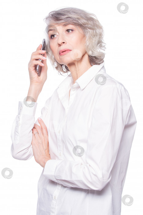 Скачать Привлекательная пожилая женщина очень внимательно слушает собеседника во время телефонного разговора с помощью смартфона, выделенного на белом фоне фотосток Ozero