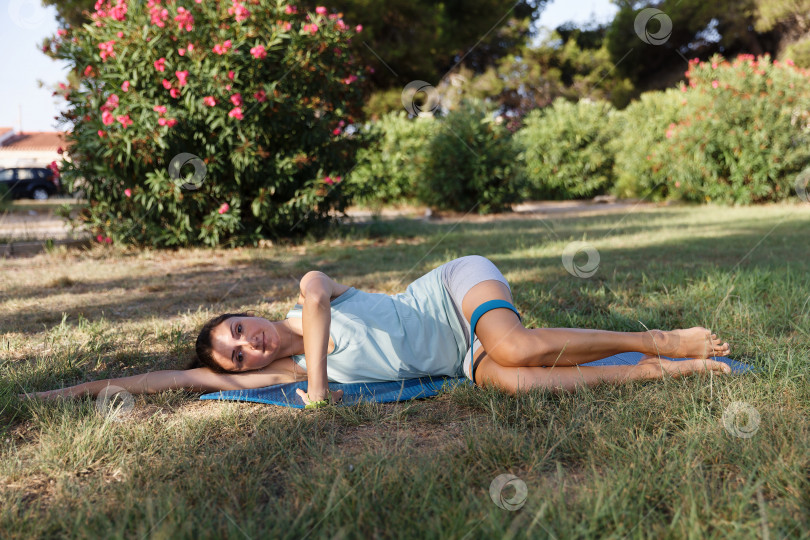 Скачать Симпатичная женщина занимается йогой в утреннем парке. Концепция здорового образа жизни на открытом воздухе. Спорт. фотосток Ozero