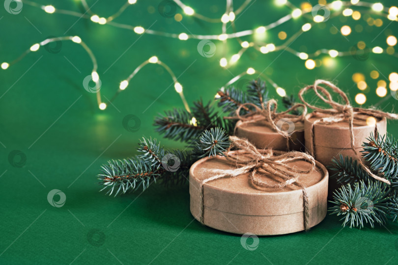 Скачать Рождественские устойчивые круглые подарочные коробки и сияющая гирлянда на зеленом фоне. Рождество без отходов, день подарков и зимние каникулы фотосток Ozero