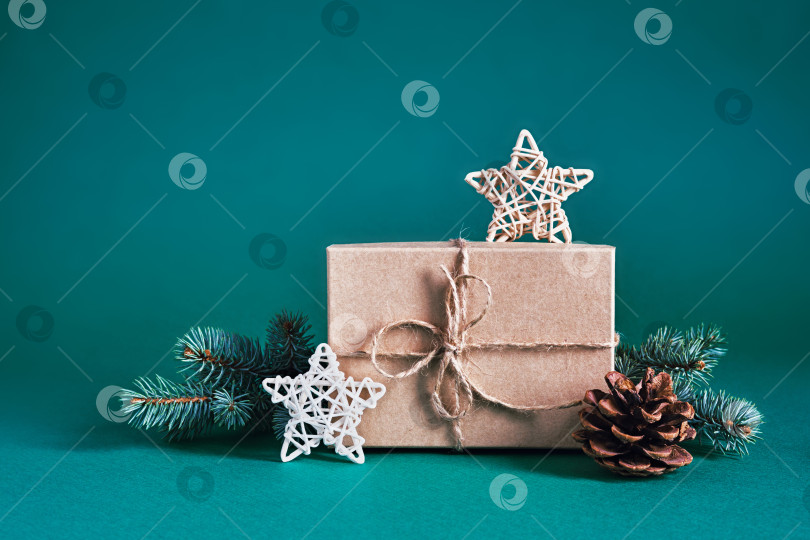Скачать Рождественская устойчивая композиция с подарочной коробкой ручной работы и натуральным декором на сине-зеленом фоне. Рождество без отходов фотосток Ozero