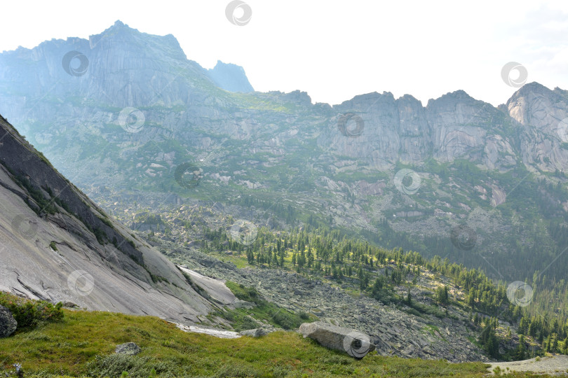 Скачать Залитое солнцем широкое ущелье в горном массиве с остроконечными вершинами в ясный летний день. фотосток Ozero