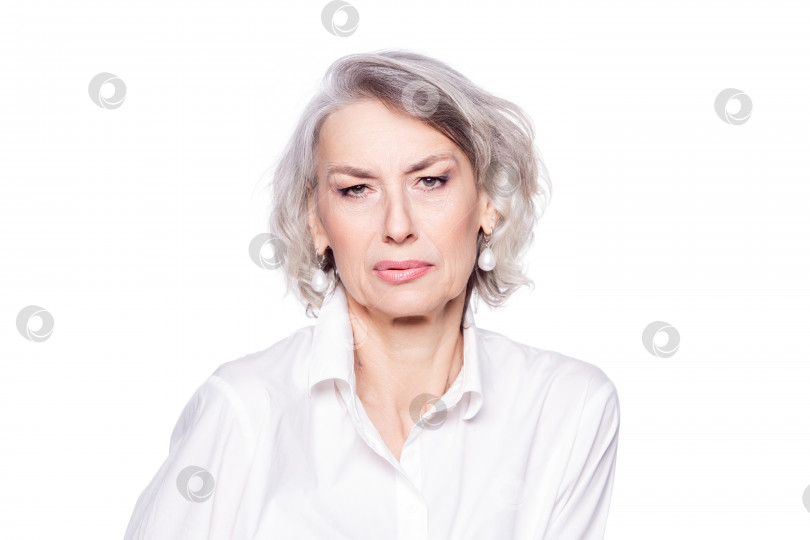 Скачать Недовольная пожилая женщина на пенсии с морщинистым ухоженным лицом выглядит разочарованной, подозрительно глядя в камеру, выделенную на белом фоне фотосток Ozero