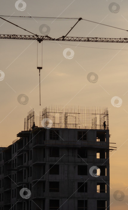 Скачать Силуэты башенных кранов на фоне вечернего неба. Дом в стадии строительства. Промышленный горизонт фотосток Ozero