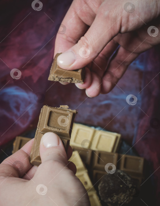 Скачать Женские руки держат шоколад ручной работы.Кондитерские изделия на темном фоне. фотосток Ozero