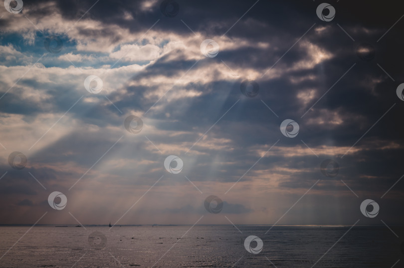 Скачать солнечные лучи пробиваются сквозь облака на рассвете, на фоне моря фотосток Ozero