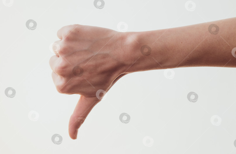 Скачать Женская рука с жестом большого пальца вниз на белом фоне фотосток Ozero