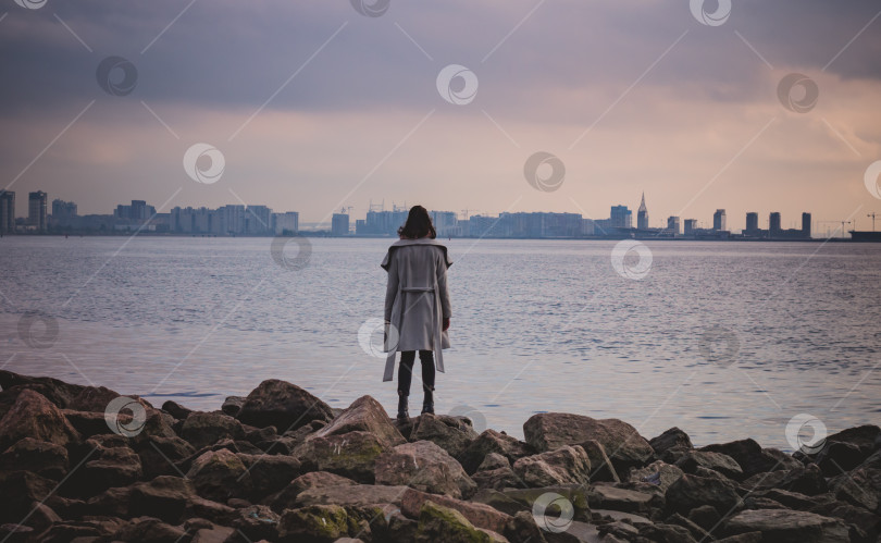 Скачать девушка смотрит на пейзаж на берегу залива.Город вдалеке фотосток Ozero