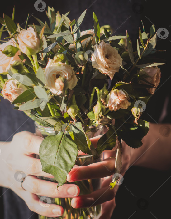 Скачать Женщина держит в руках букет цветов.Весенние цветы, освещенные солнцем. фотосток Ozero