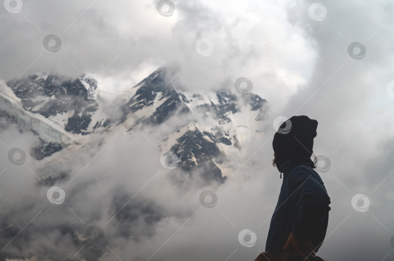 Скачать Спортивная девушка смотрит на заснеженные вершины гор. Экстремальная погода в высокогорье. фотосток Ozero