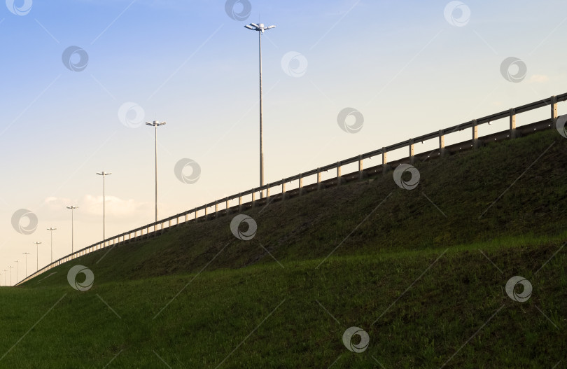 Скачать Шоссе в зеленом поле на фоне голубого неба. Дорожный пейзаж. фотосток Ozero
