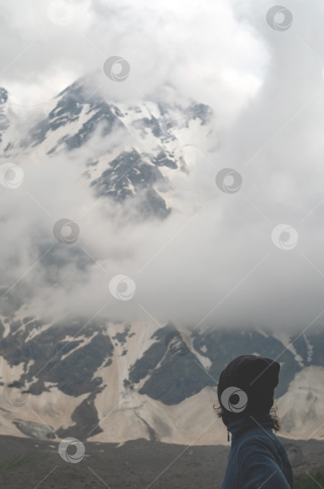 Скачать Спортивная девушка смотрит на заснеженные вершины гор. Экстремальная погода в высокогорье. фотосток Ozero