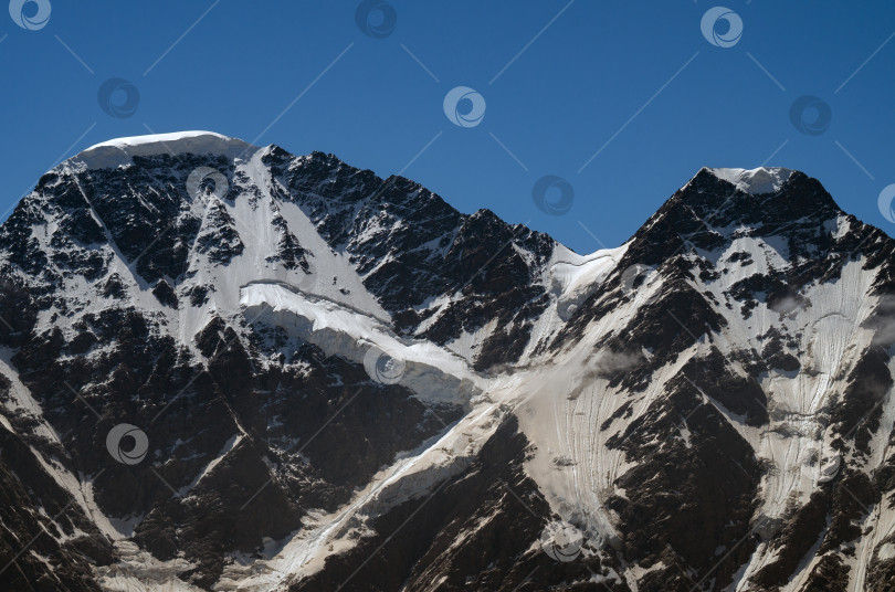 Скачать Заснеженный горный склон с облаками на фоне голубого неба. Кавказские горы летом. фотосток Ozero
