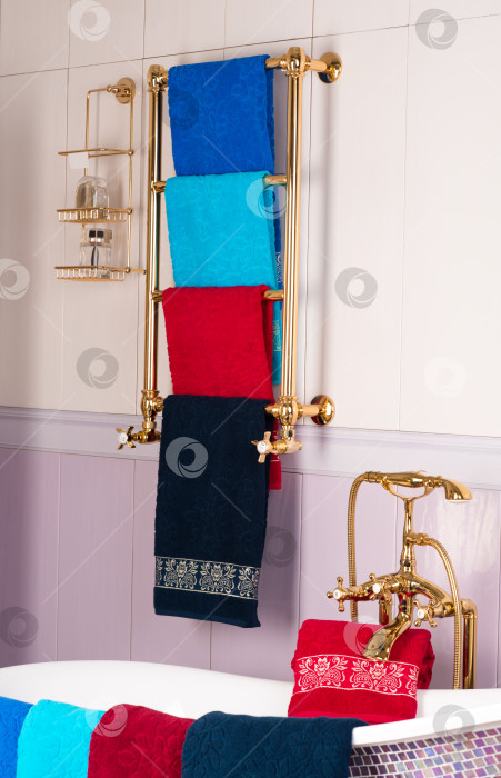 Скачать Вертикальный снимок разноцветных бамбуковых полотенец, висящих на золотой вешалке в ванной комнате фотосток Ozero