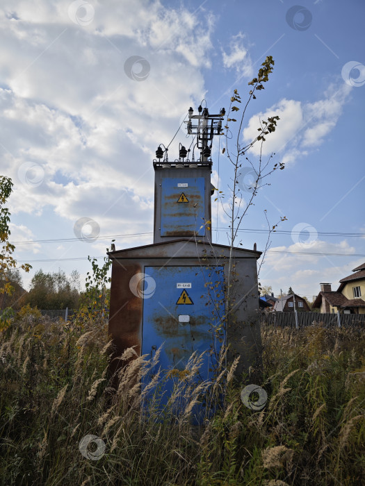 Скачать Старая ржаво-синяя трансформаторная будка в поле на фоне неба фотосток Ozero