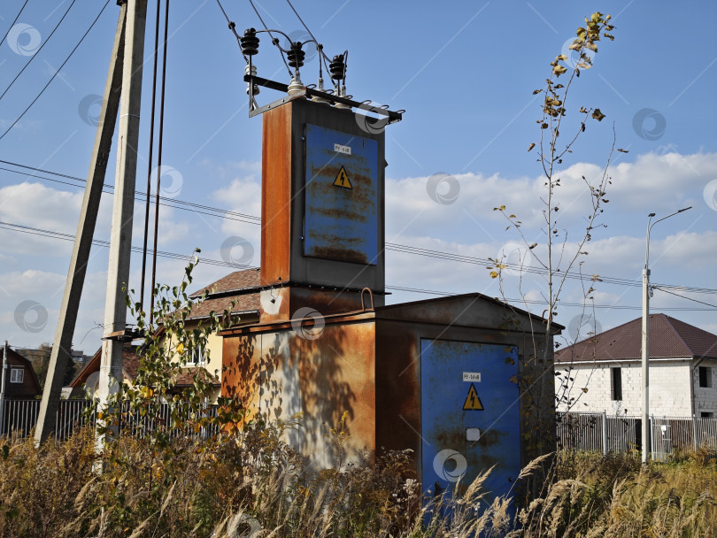 Скачать Старая ржаво-синяя трансформаторная будка в поле на фоне неба фотосток Ozero