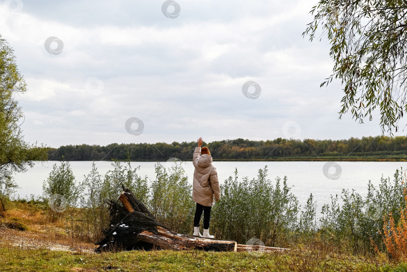 Скачать Девушка в светлой куртке и коричневой шляпке смотрит на осенний пейзаж фотосток Ozero