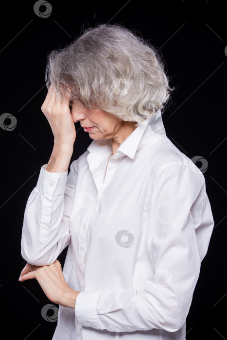 Скачать Вид сбоку портрет старой, но современной модной женщины, страдающей от головной боли или мигрени, держащей голову в руках с выражением отчаяния, выделенным на черном фоне фотосток Ozero