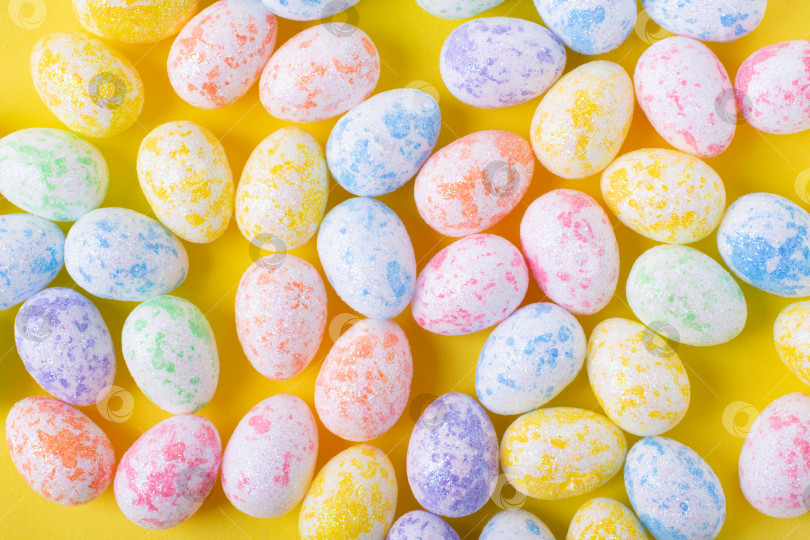 Скачать Пасхальный фон с разноцветными декоративными яйцами на желтом фоне. Праздничная плоская лежанка. фотосток Ozero