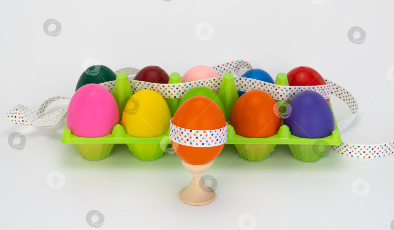 Скачать пасхальное яйцо на деревянной подставке. разноцветные яйца в коробке. пластиковая упаковка. украшен праздничной лентой фотосток Ozero