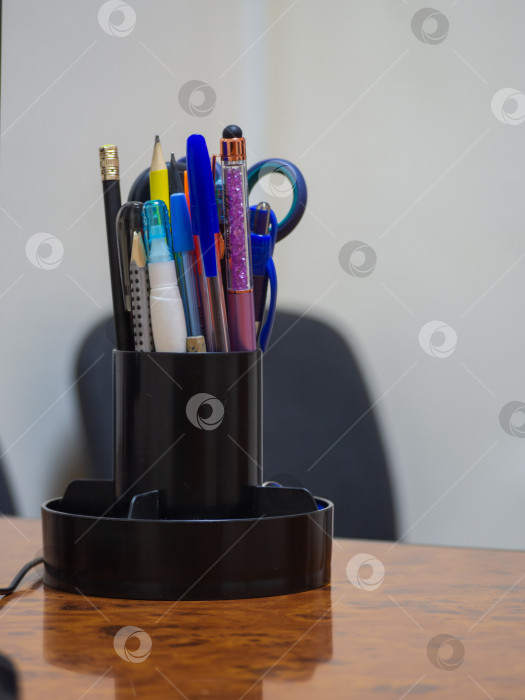 Скачать Канцелярские принадлежности в органайзере на рабочем столе. Крупный план органайзера с использованными ручками и карандашами на деревянном столе в офисе. Офисные принадлежности. Ручки в стаканчике на столе для совещаний фотосток Ozero