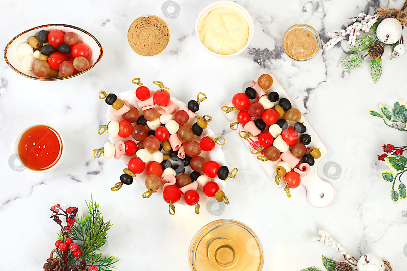 Скачать Рождественские и новогодние блюда, набор закусок и освежающих напитков для праздничного стола. Тарелка с канапе из помидоров, сыра моцарелла, оливок, маслин и винограда на мраморном столе, фотосток Ozero