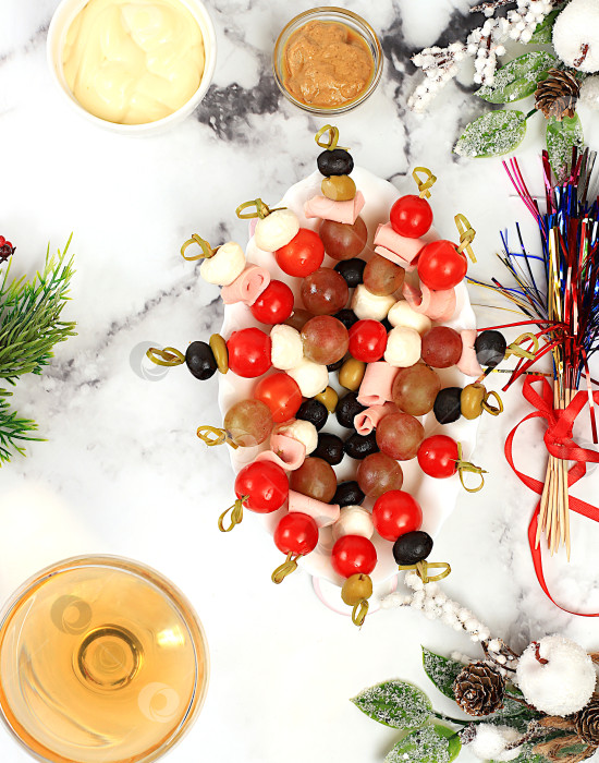 Скачать Рождественские и новогодние блюда, набор закусок и освежающих напитков для праздничного стола. Тарелка с канапе из помидоров, сыра моцарелла, оливок, маслин и винограда на мраморном столе фотосток Ozero
