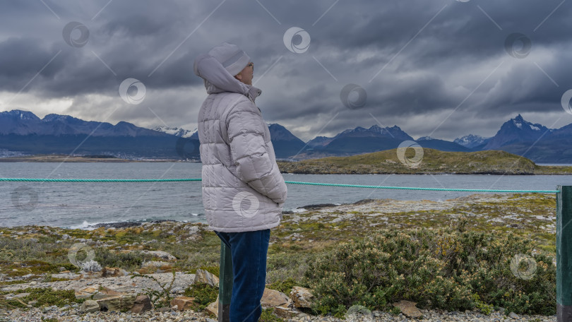 Скачать Мужчина в пуховике и шляпе стоит на острове фотосток Ozero
