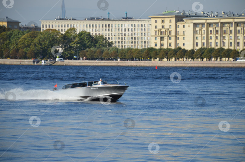 Скачать Санкт-Петербург, Россия – 09.23.2023: Катер с флагом Санкт-Петербурга быстро проплывает мимо Петровской набережной фотосток Ozero