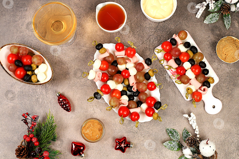 Скачать Рождественские и новогодние блюда, набор закусок и освежающих напитков для праздничного стола. Тарелка с канапе из помидоров, сыра моцарелла, оливок, маслин и винограда на мраморном столе, фотосток Ozero
