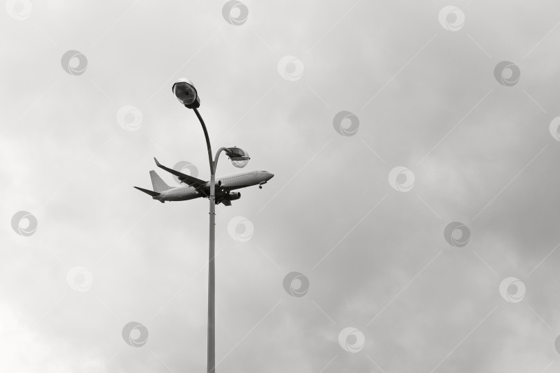 Скачать Уличный фонарь на фоне неба и пролетающий самолёт, чёрно-белый кадр - Санкт-Петербург, Россия, Июнь 2021 фотосток Ozero