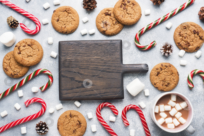 Скачать Печенье с шоколадной крошкой, рождественская тростниковая карамель, какао в чашечке и зефирные рожки - украшения на сером фоне. Скопируйте рамку пробела. фотосток Ozero