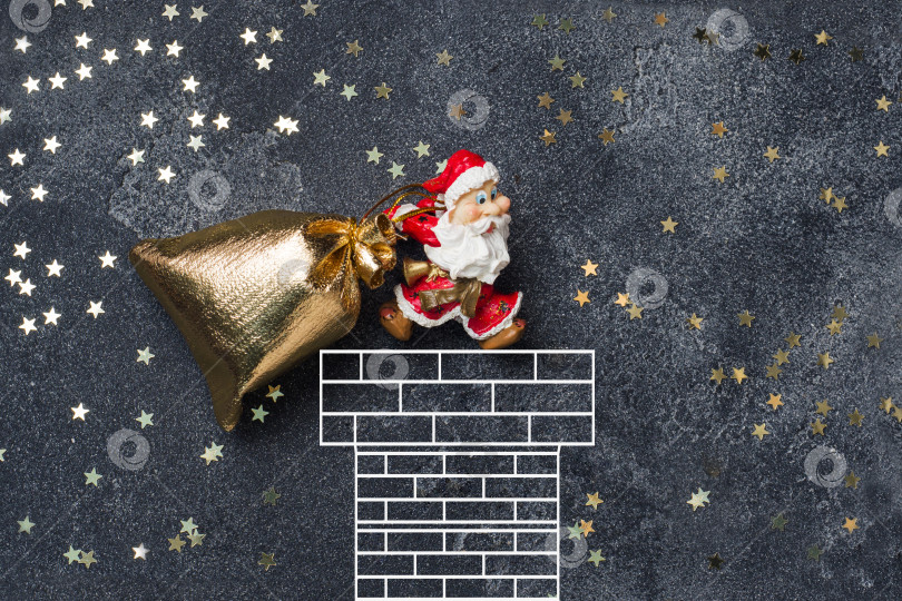 Скачать Концепция рождественской ночи. Санта затаскивает мешок с подарками в дымоход. Темный звездный фон. фотосток Ozero