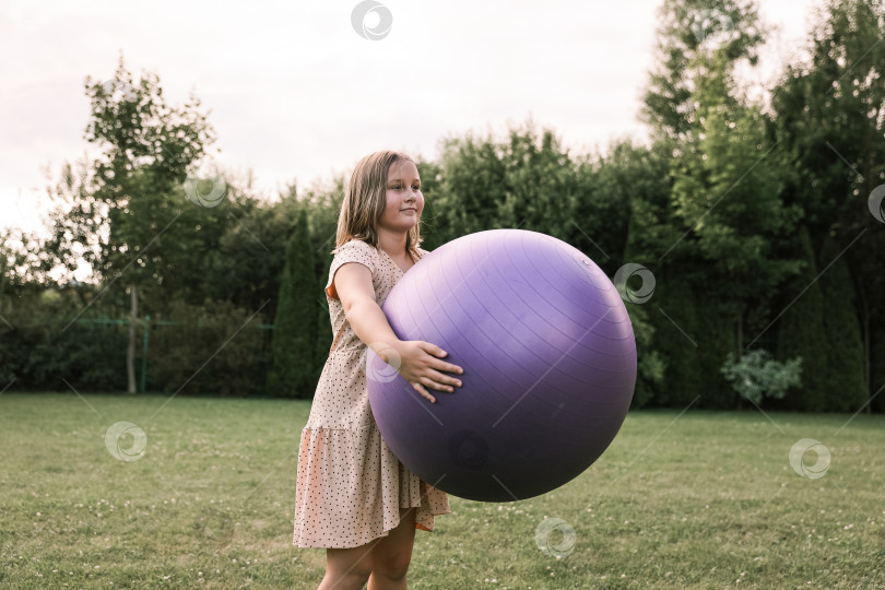 Скачать Девочка играет с большим мячом на лужайке во дворе дома жарким летом, концепция здорового образа жизни фотосток Ozero