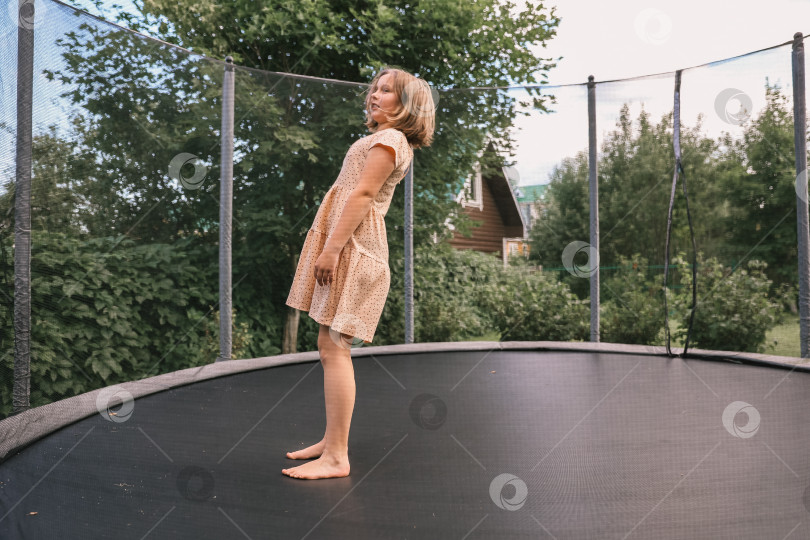 Скачать Девочка прыгает на батуте во дворе дома фотосток Ozero