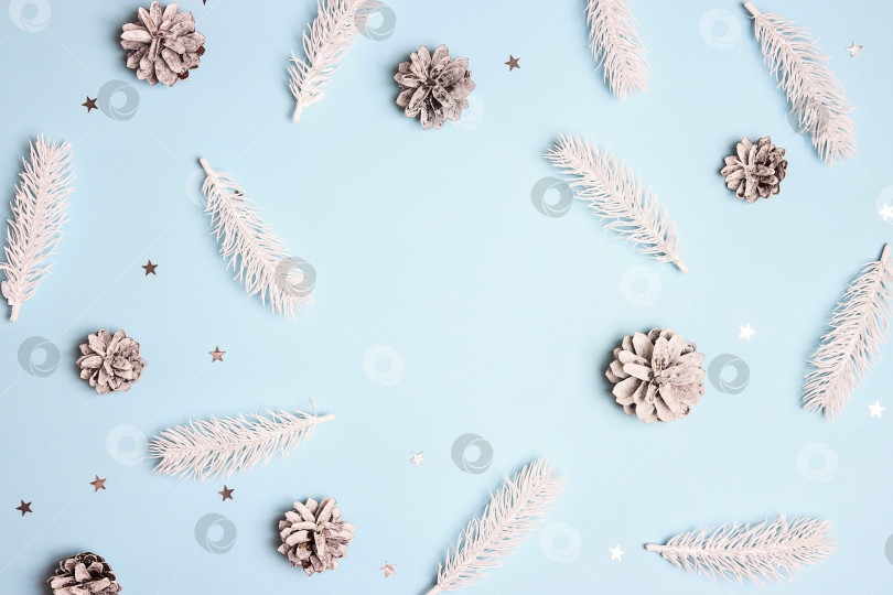 Скачать Рождественская рамка с белыми еловыми ветками, шишками и серебряными звездами на синем фоне. фотосток Ozero