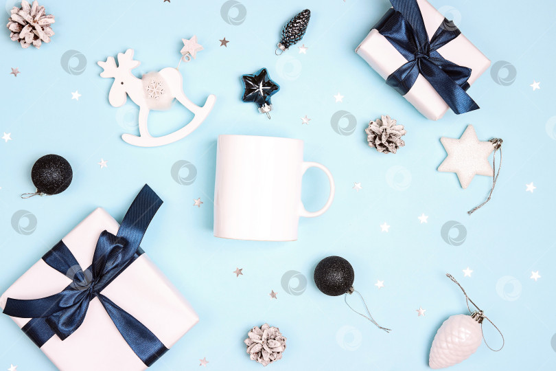 Скачать Белая кофейная кружка с рождественскими украшениями на синем фоне. фотосток Ozero