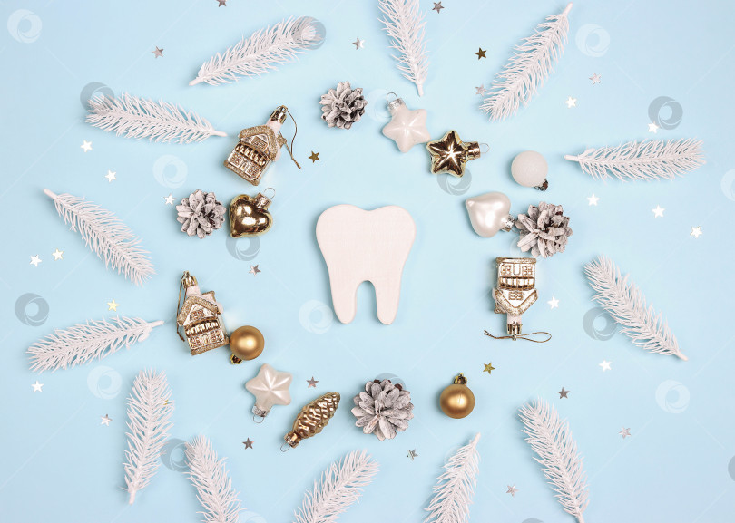 Скачать Белый зуб в окружении рождественских золотых и белых украшений на синем фоне. фотосток Ozero
